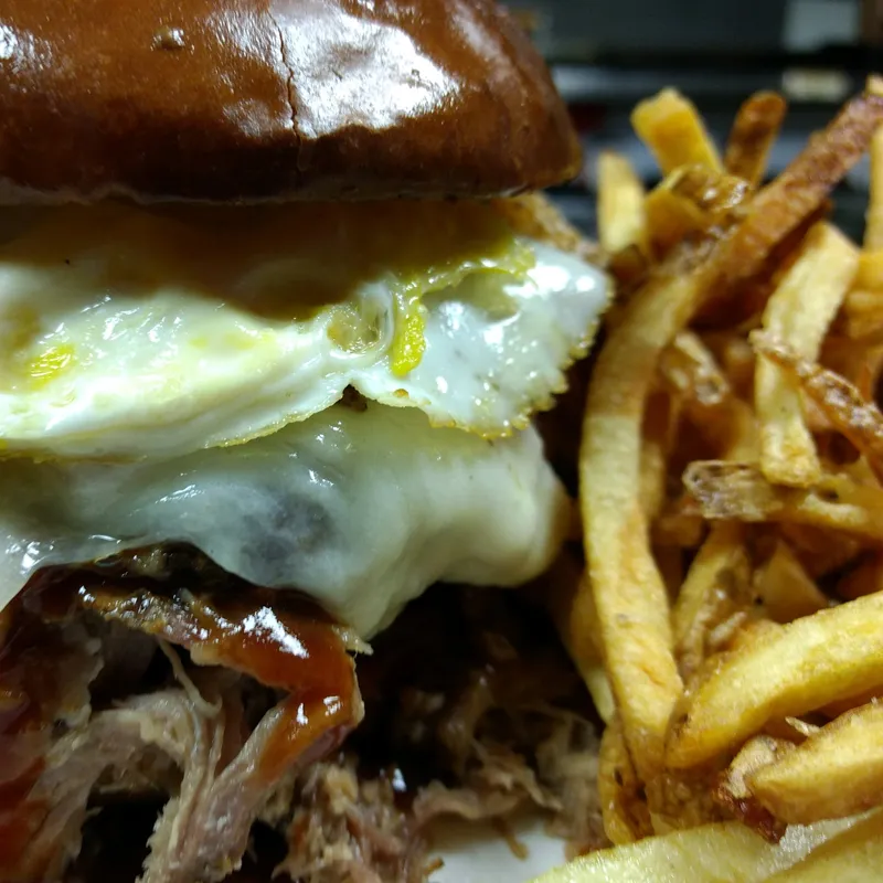 Burger topped with a fried egg and a side of fries