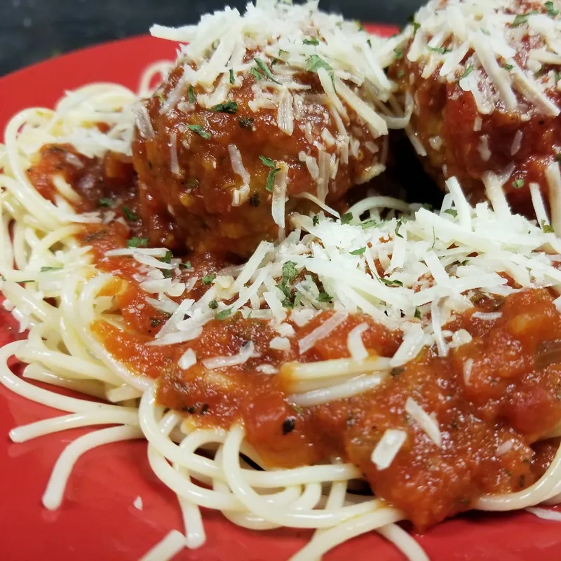 Spaghetti and meatballs under shredded cheese